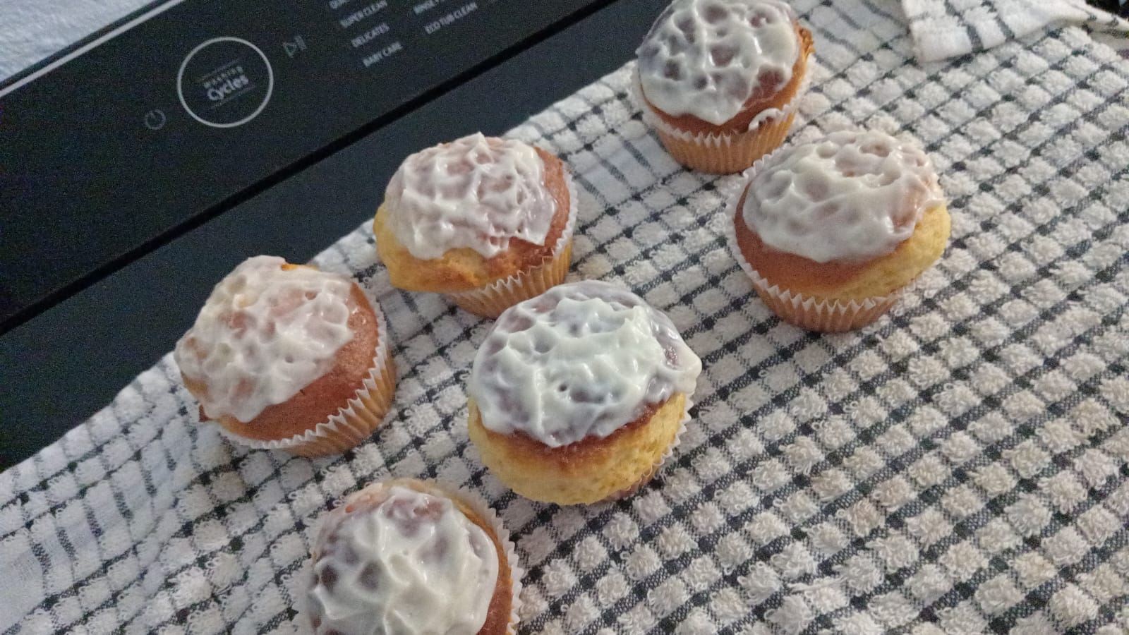 Freshly iced muffins cooling on a towel
